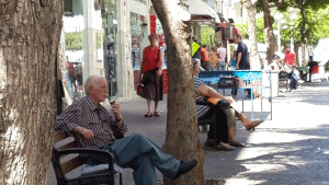 איש זקן יושב על ספסל ברחוב